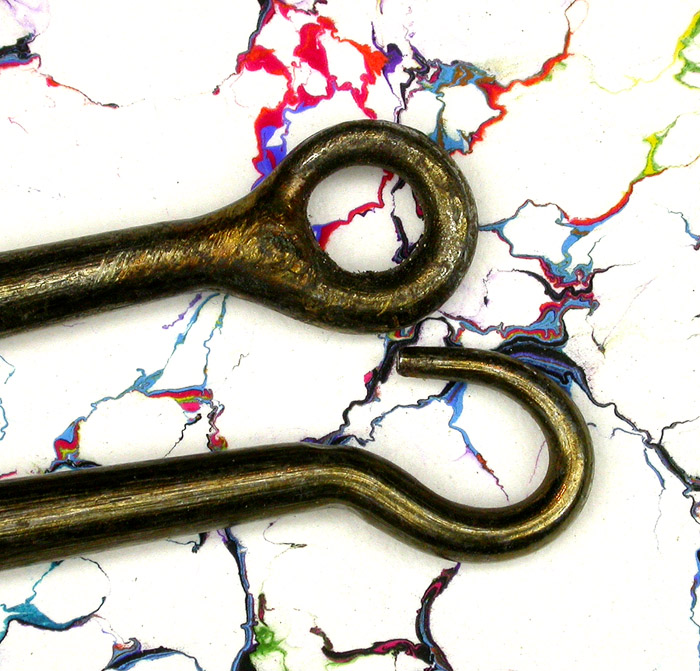 23b Mills, 13/0, knife edge, ring eye. These two hooks are almost identical except for the eyes. One has a hand filed tapered and welded ring eye while the other seems unfinished. Also, the hooks are lined up perfectly at the bends and you can see that the lower hook would be longer than the other when the eye was closed and welded. More indication of hand worked hooks. Ca 1900. Part of the 1900’s collection.